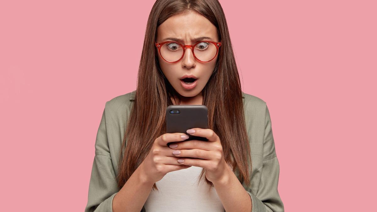 Una mujer joven lee con sorpresa un sms.