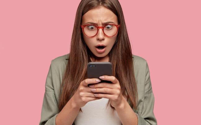 Una mujer joven lee con sorpresa un sms.