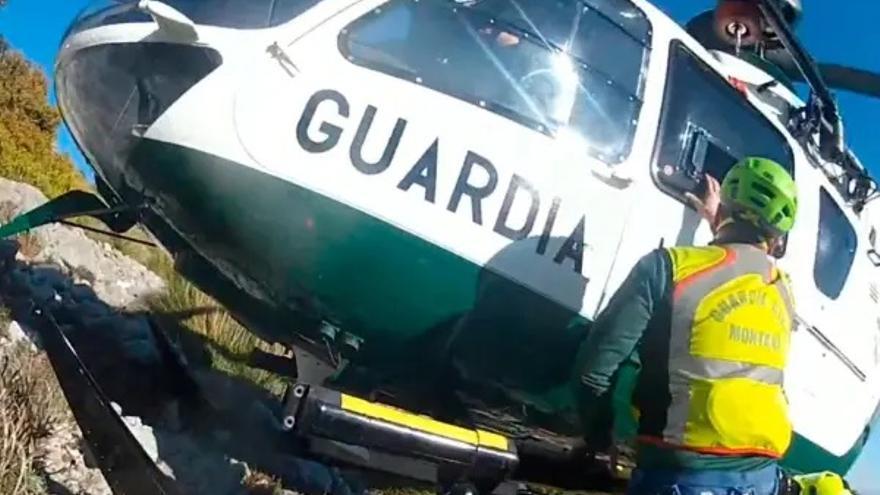 Un agente del Greim junto al helicóptero de la unidad realizando un rescate