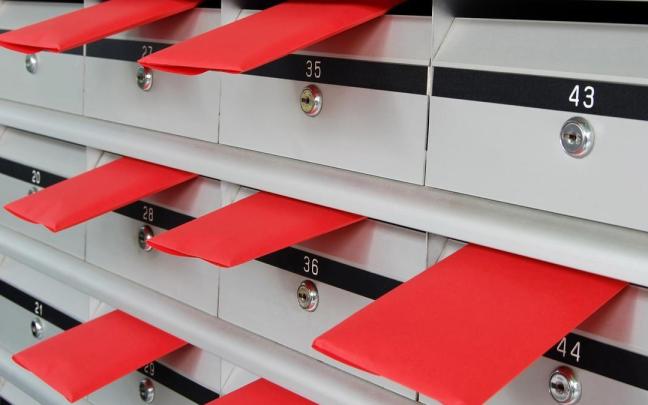 Varios sobres sobresalen de unos buzones en una comunidad de vecinos.