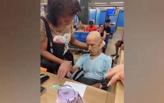 La mujer sujeta la cabeza del finado e intenta que firme el documento para que se le conceda el préstamo. / Twitter La mujer sujeta la cabeza del finado e intenta que firme el documento para que se le conceda el préstamo.