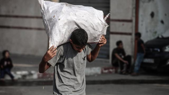 Un joven palestino carga un saco de ayuda humanitaria en Al-Bureij.