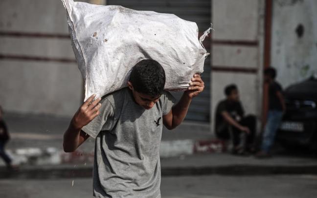 Un joven palestino carga un saco de ayuda humanitaria en Al-Bureij.