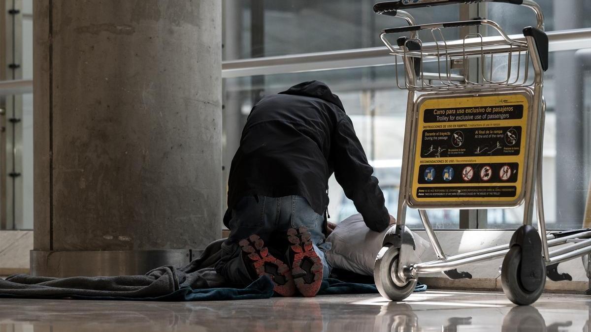 Una persona se prepara para pernoctar en el aeropuerto Adolfo Suárez Madrid-Barajas.