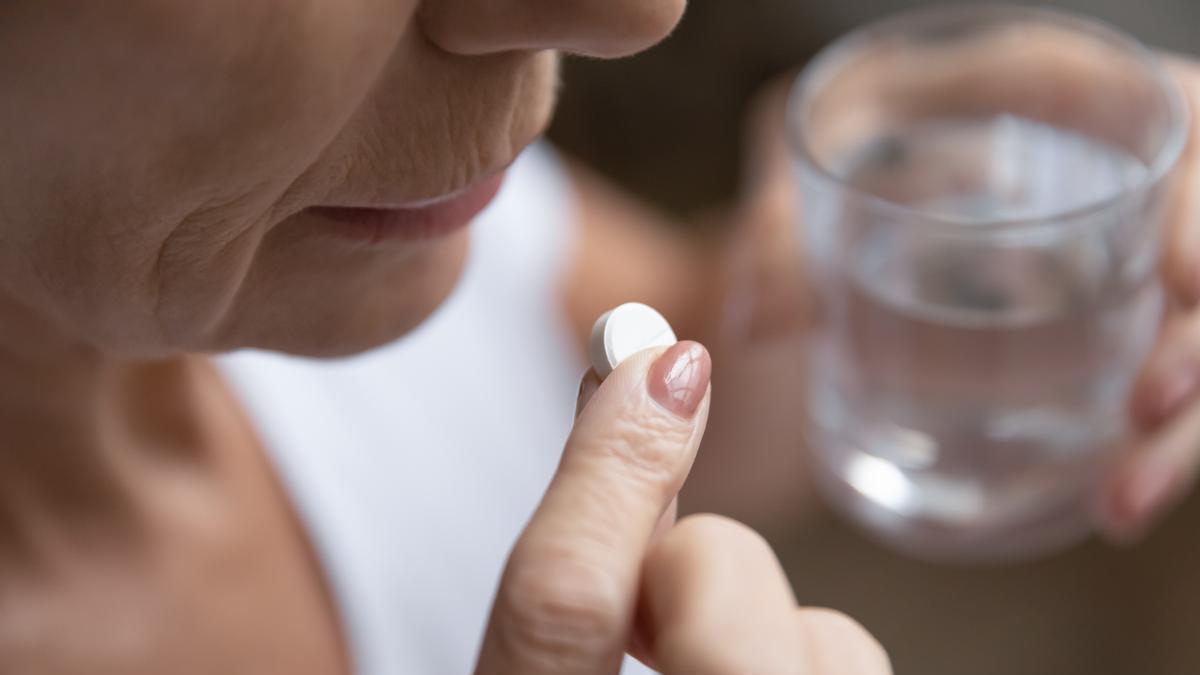 Una mujer toma una pastilla, de las muchas que componen su pastillero diario.