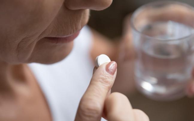 Una mujer toma una pastilla, de las muchas que componen su pastillero diario. Una mujer toma una pastilla, de las muchas que componen su pastillero diario.
