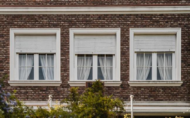 Ventanas con persianas de madera enrollables en la fachada de un edificio. Ventanas con persianas de madera enrollables en la fachada de un edificio.