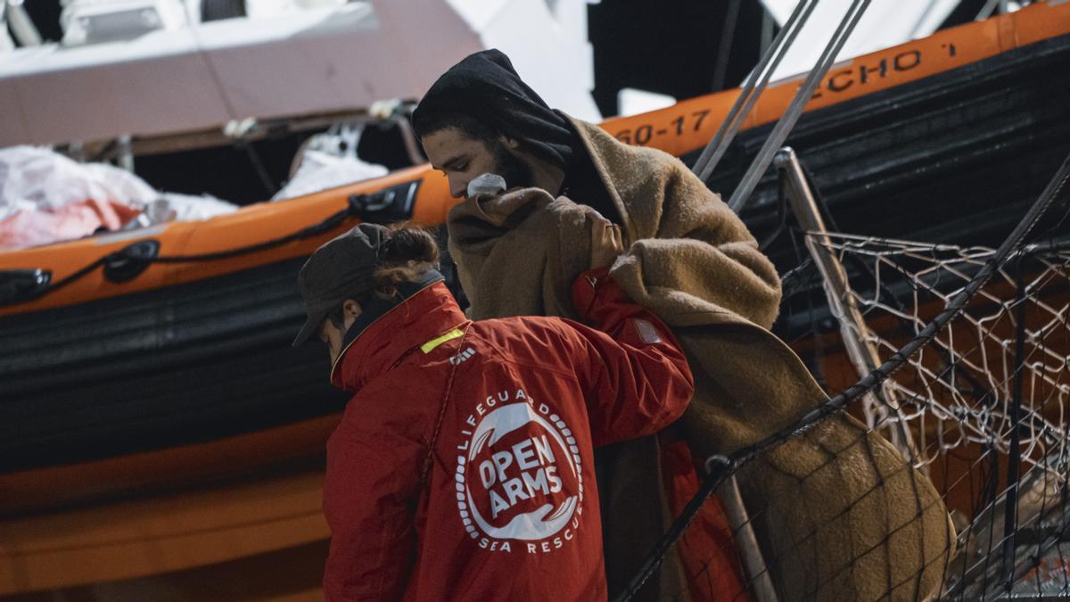 Un miembro de Open Arms ayuda a un migrante a desembarcar en el puerto italiano de Crotone.