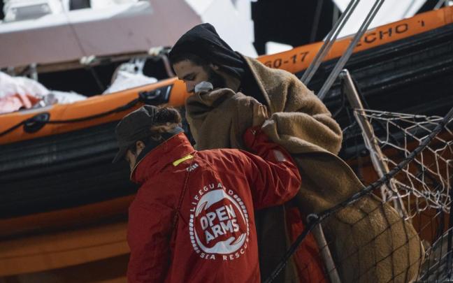 Un miembro de Open Arms ayuda a un migrante a desembarcar en el puerto italiano de Crotone.