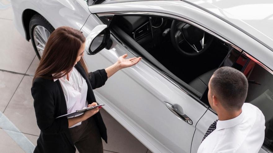 Una vendedora enseña las características de un vehículo a un cliente.