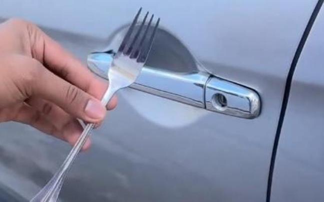 Un tenedor, junto a la cerradura de un coche.