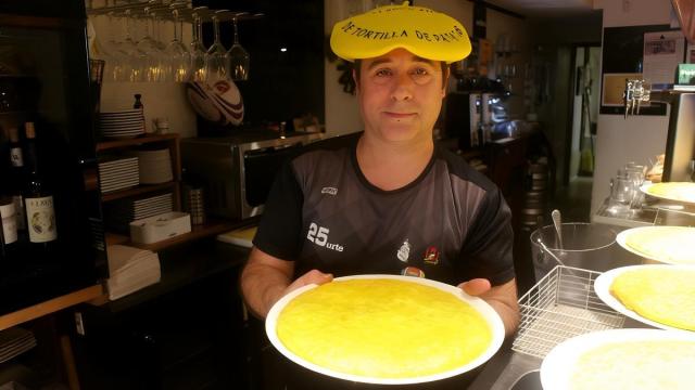 Con la txapela del título de subcampeón de Euskadi, Asier Antia muestra una de las sabrosas tortillas que se sirven en la barra del bar Ezkiña.