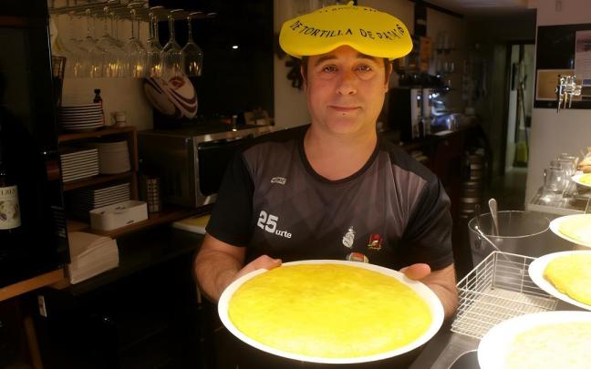 Con la txapela del título de subcampeón de Euskadi, Asier Antia muestra una de las sabrosas tortillas que se sirven en la barra del bar Ezkiña.