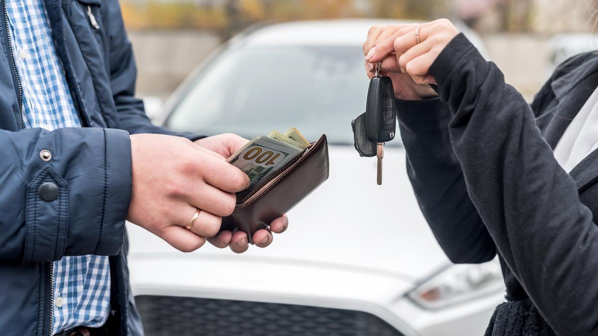 Dos personas sellan la venta de un coche.