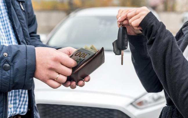 Dos personas sellan la venta de un coche.