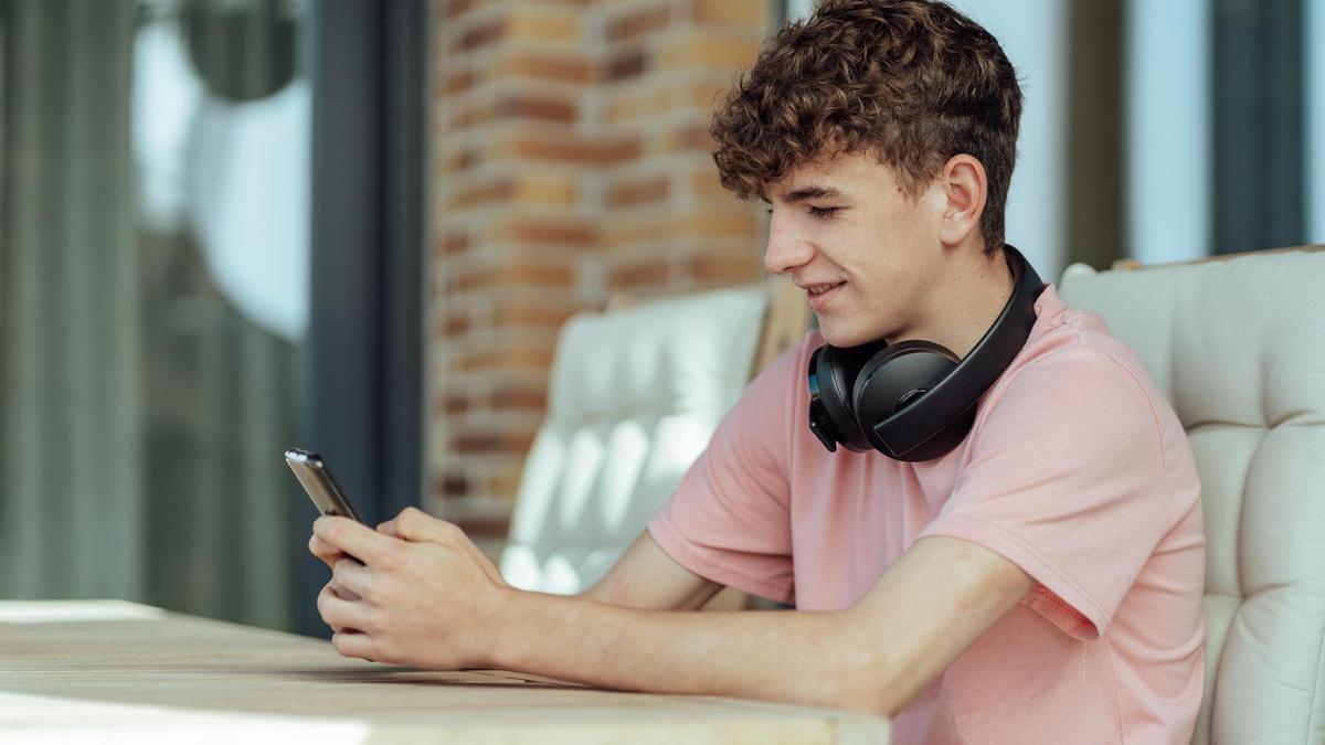 Un joven escribe un mensaje en el móvil.