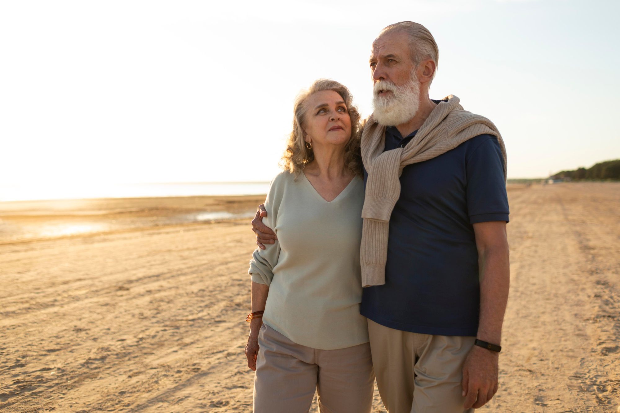 Una pareja mayor camina por la playa.