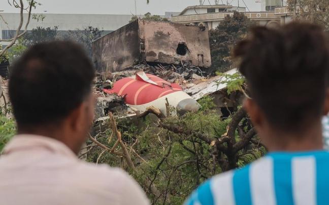 Dos hombres observan los restos del avión accidentado en la India.