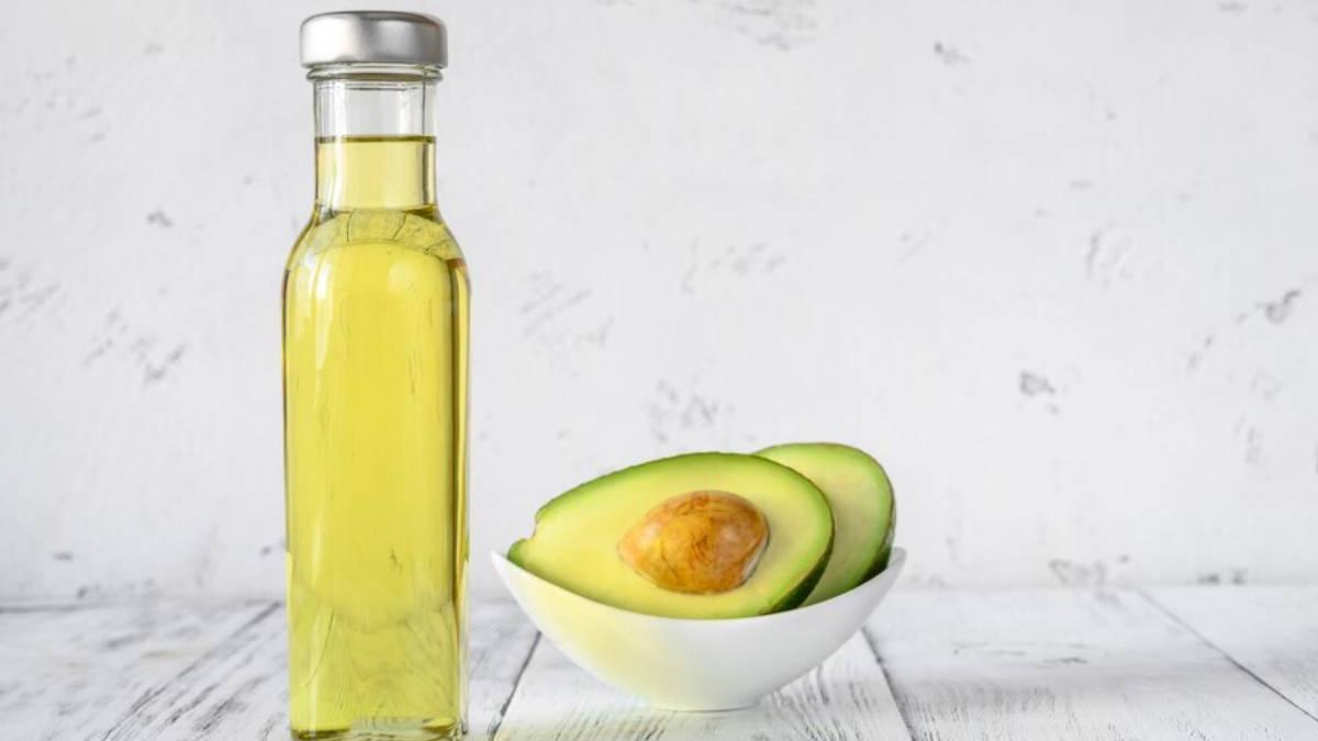 Botella de cristal al lado de un aguacate abierto por la mitad