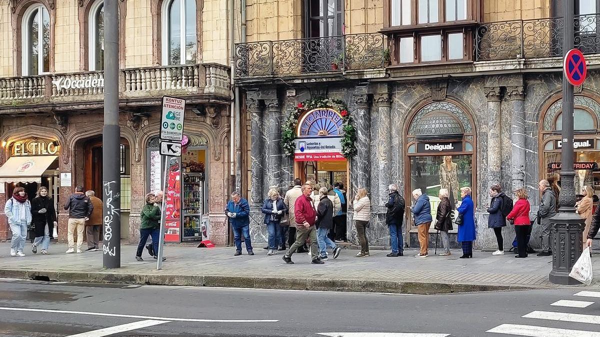 Personas hacen cola en una administración de Bilbao para comprar lotería.