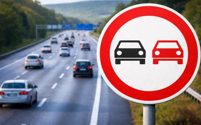 Una señal de prohibido adelantar junto a una carretera.