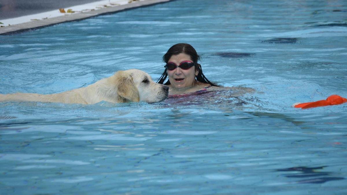 Una mujer se baña junto a un perro en una piscina alavesa coincidiendo con el final de la temporada de verano.