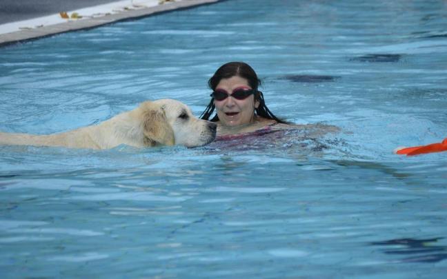 Una mujer se baña junto a un perro en una piscina alavesa coincidiendo con el final de la temporada de verano.