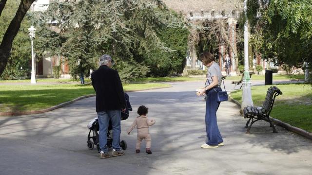 Dos personas mayores disfrutan de un paseo por el parque en compañía de su nieta.