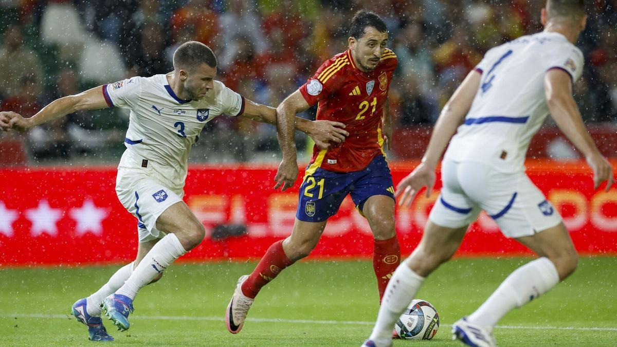 Mikel Oyarzabal intenta escaparse de dos futbolistas serbios en el partido de este martes en Córdoba. / EFE/JULIO MUNOZ