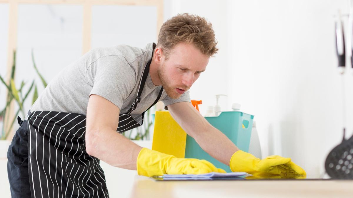 Un hombre limpia la encimera de la cocina.