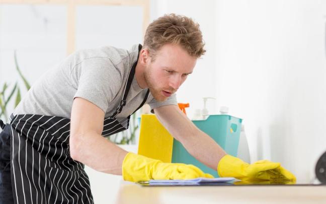 Un hombre limpia la encimera de la cocina.