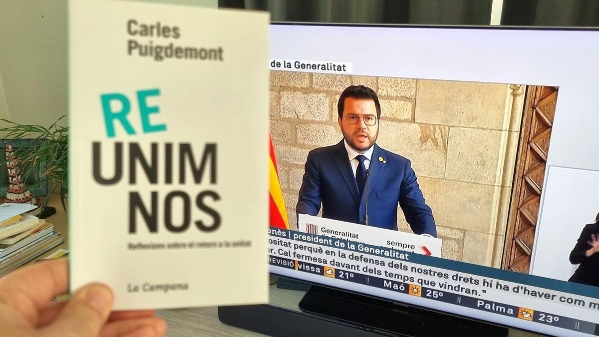 Carles Puigdemont escucha la comparecencia de Pere Aragonès y muestra el libro que escribió bajo el título ‘Reunámonos’.