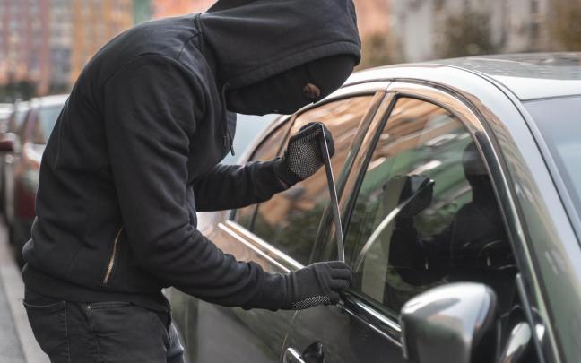 Un ladrón intenta entrar en un coche.