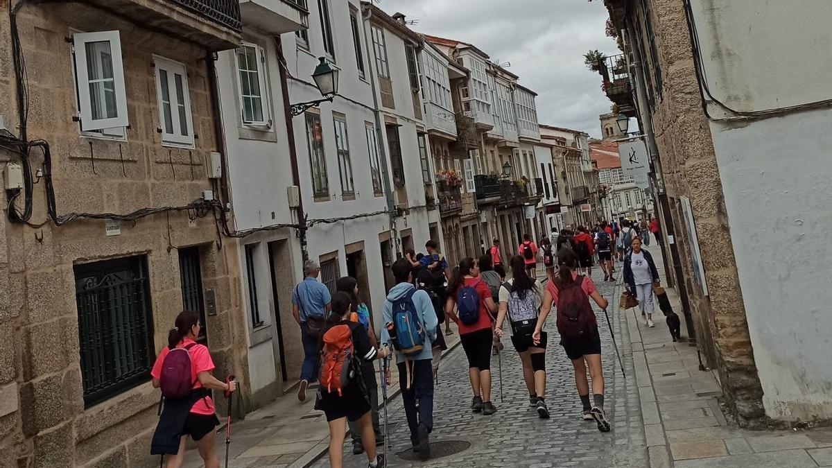 Peregrinos bajan por el medio de la Rúa de San Pedro, en Santiago de Compostela.