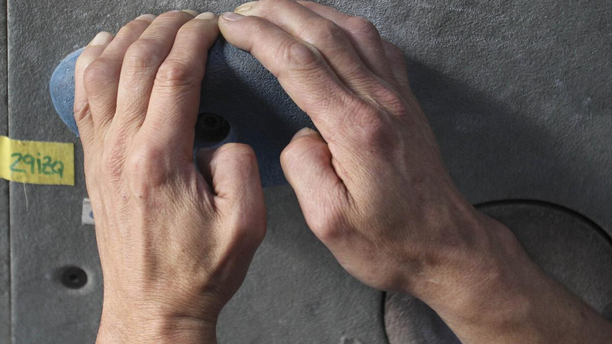 Detalle de las manos de una persona en un rocódromo.