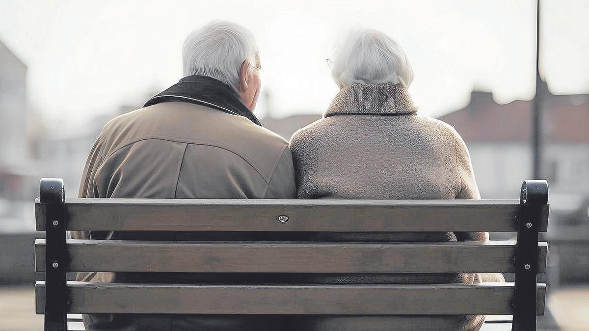 Una pareja de jubilados, sentada en un banco cercano a su domicilio.