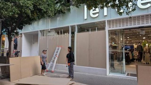 Trabajadores protegen los escaparates de una tienda de ropa.