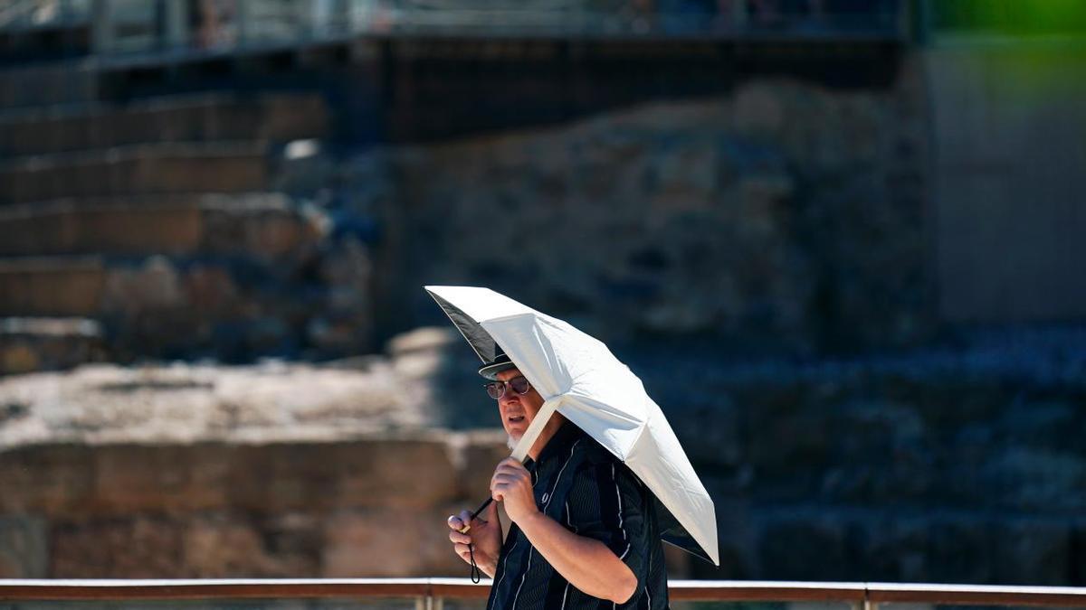 Un hombre se protege del sol con un paraguas.