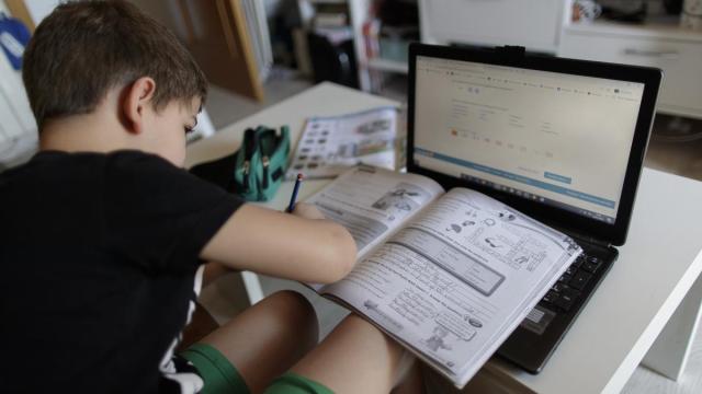 Un alumno primaria hace deberes asignatura ingles varios libros ordenador.