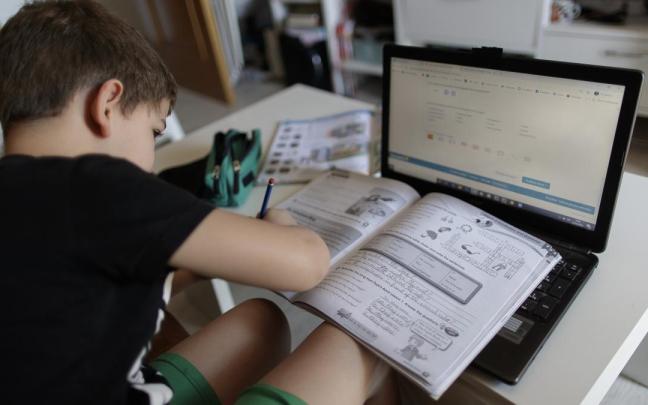 Un alumno primaria hace deberes asignatura ingles varios libros ordenador.