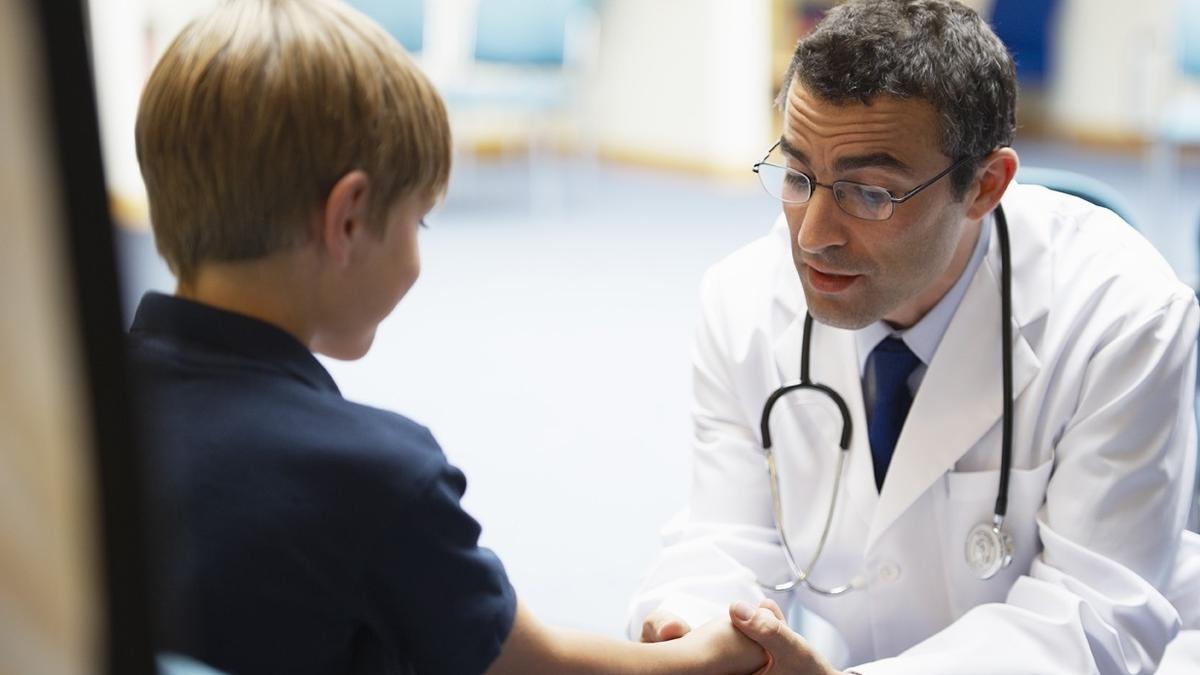 Un pediatra atiende a un niño en su consulta.