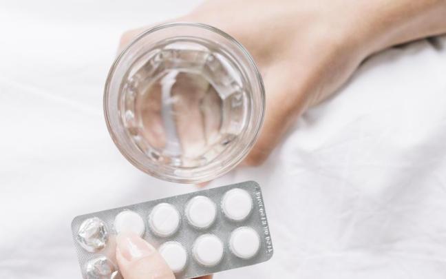 Una mujer con vaso de agua y pastillas. Una mujer con vaso de agua y pastillas.