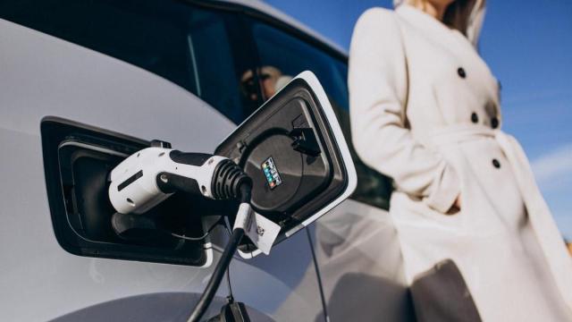 Una mujer recarga su coche eléctrico en un punto de carga.