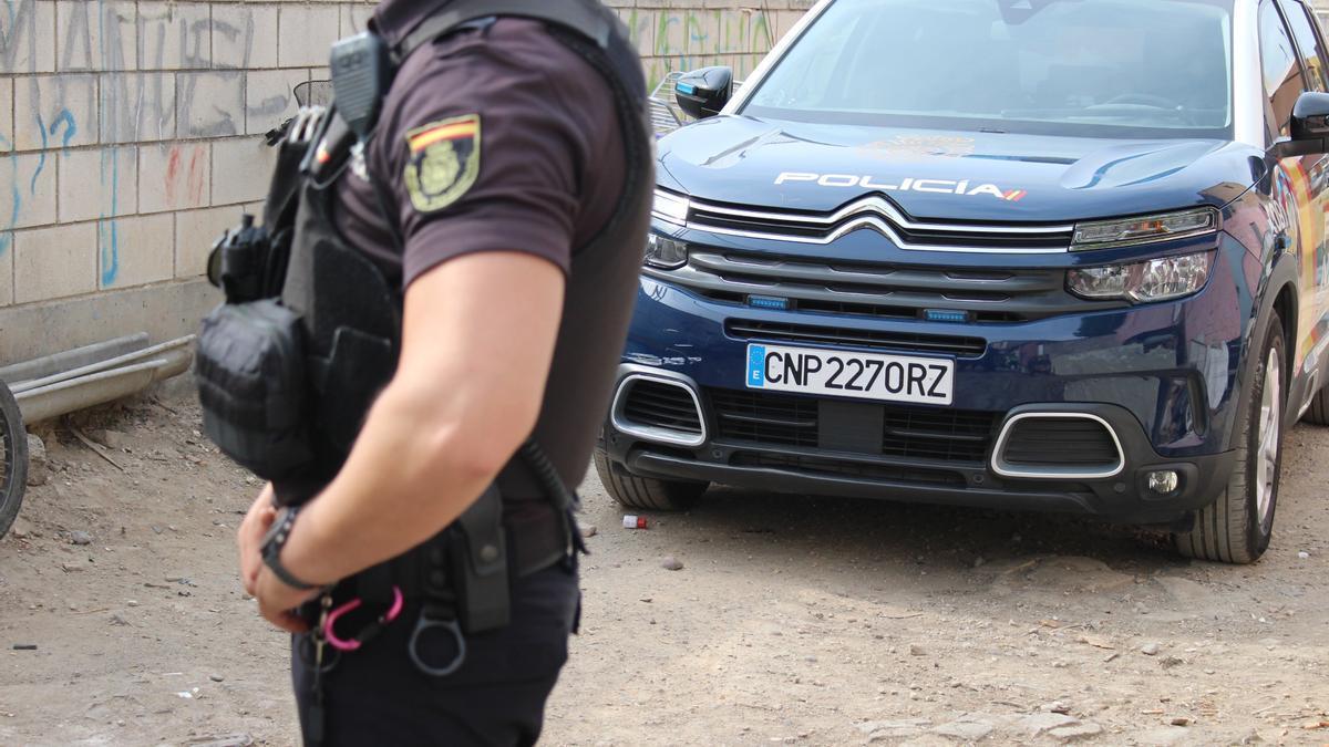 Imagen de un agente y un coche de la Policía Nacional