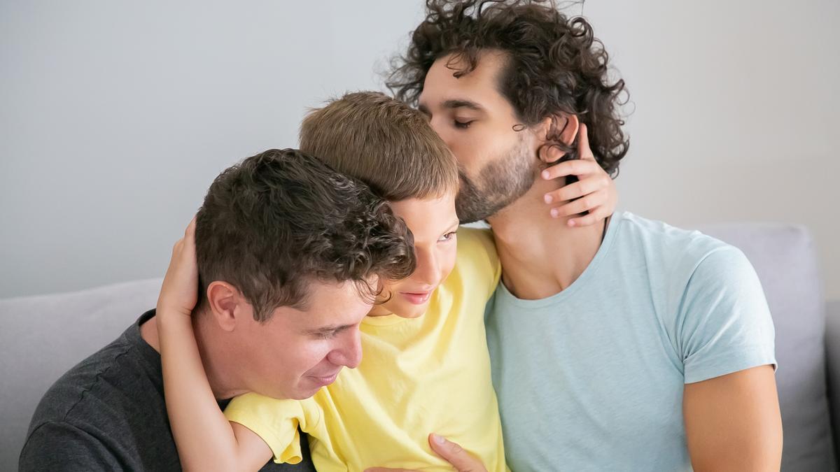 Dos padres abrazan y besan a su hijo.