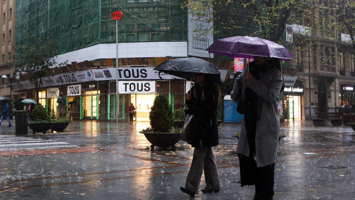 Dos personas se cubren con paraguas en un día lluvioso de Bilbao.