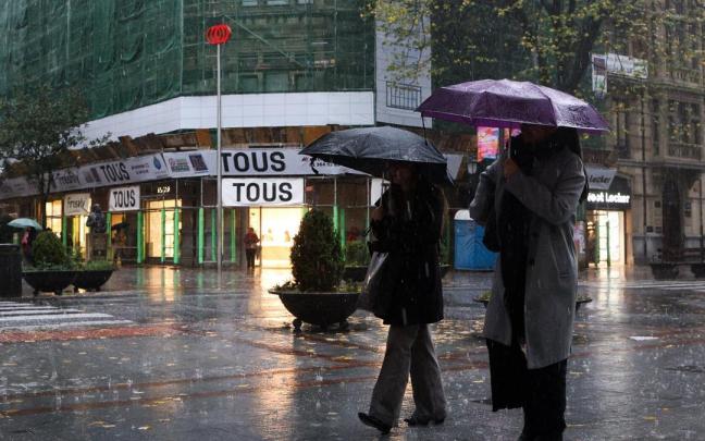 Dos personas se cubren con paraguas en un día lluvioso de Bilbao.