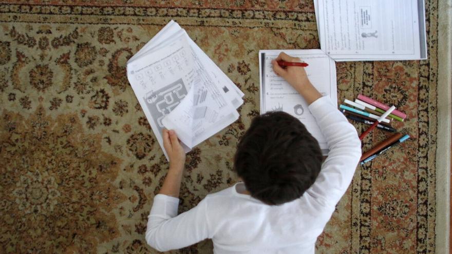 Un niño realiza ejercicios matemáticos en su casa.