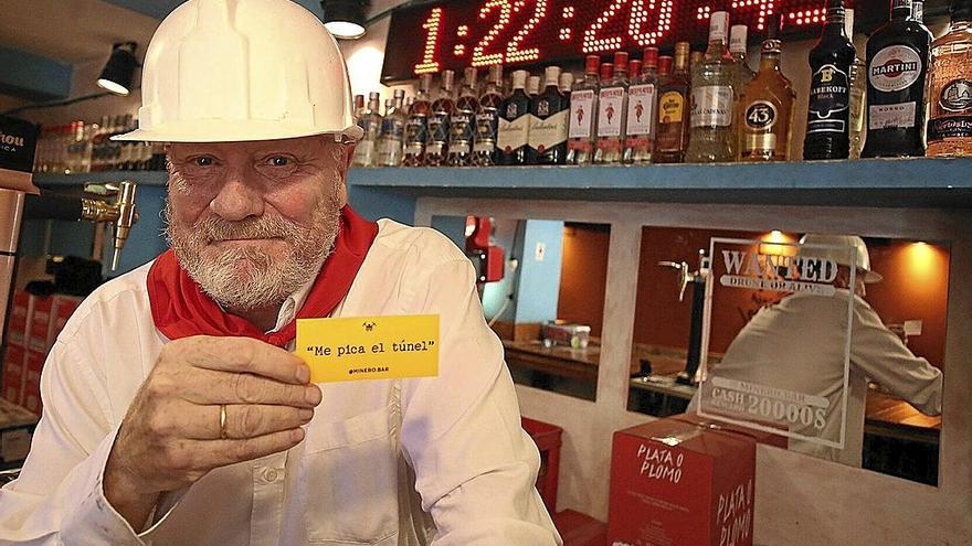 Patxi Larumbe, con el casco, tal y como hace de minero este mediodía en su bar de Jarauta, ante el reloj de las horas de borrachera.