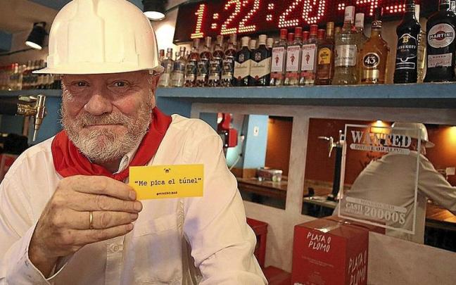 Patxi Larumbe, con el casco, tal y como hace de minero este mediodía en su bar de Jarauta, ante el reloj de las horas de borrachera.